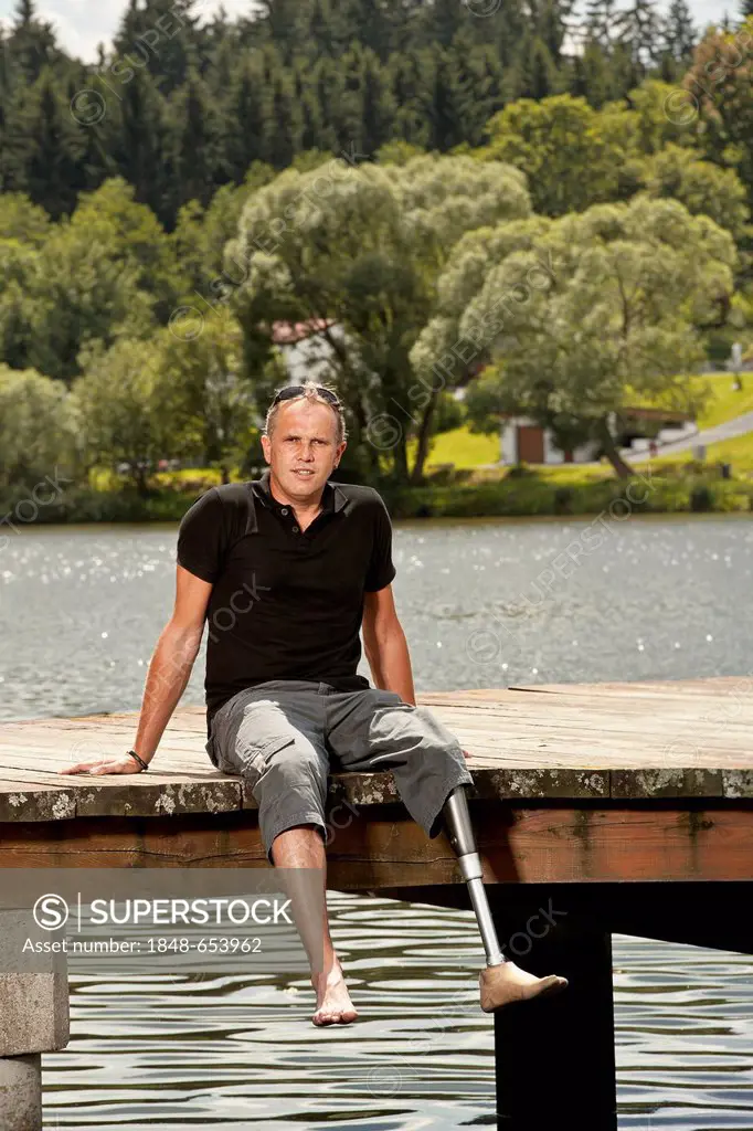 Man with a prosthetic leg sitting on a jetty