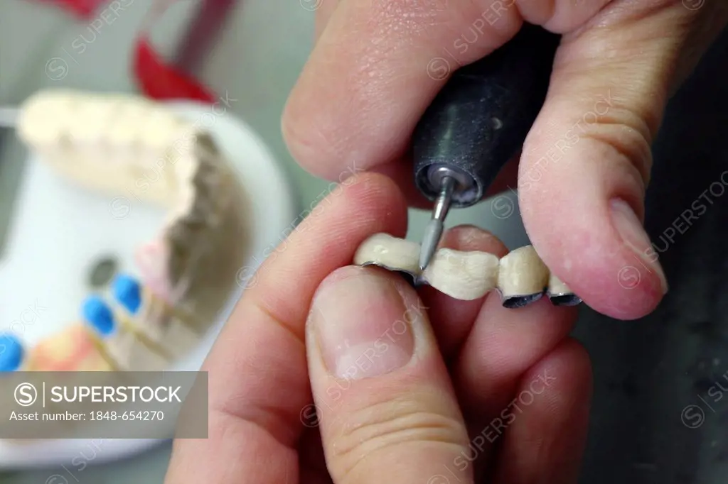 Dental laboratory, manufacture of a dental prosthesis by a master craftsman, grinding, separation, of a ceramic-veneered dental bridge