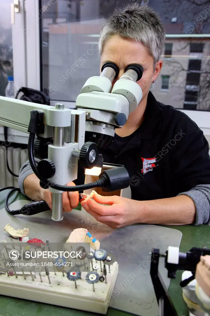 Dental laboratory, manufacture of a dental prosthesis by a master craftsman, working on a dental bridge under a stereo microscope