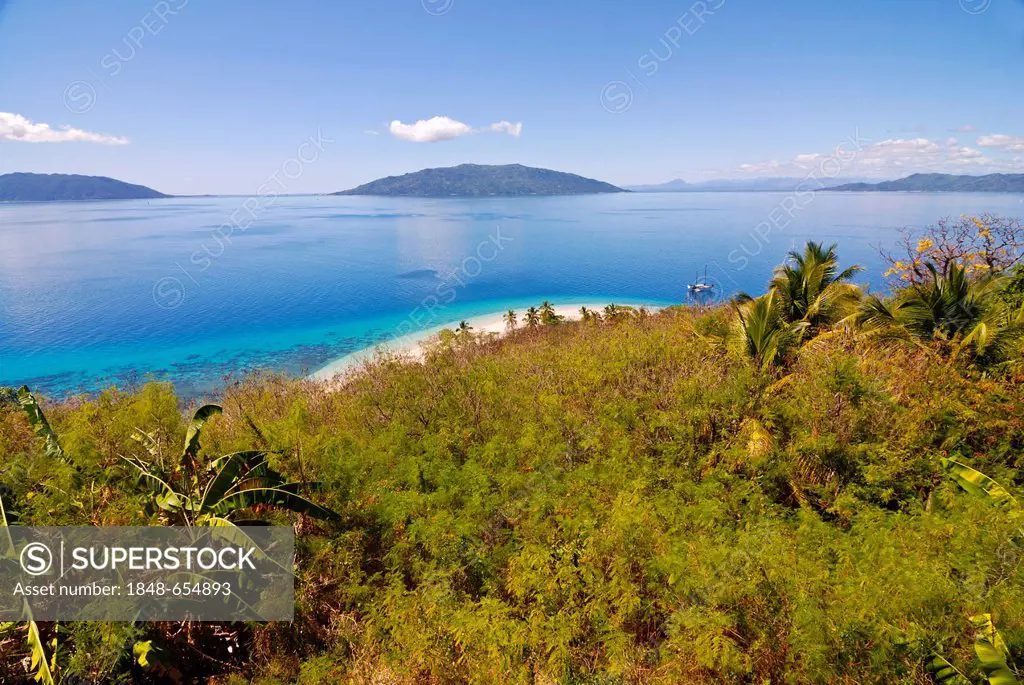 The crystal clear waters and white sand beach of Nosy Tanikely, in the distance, Nosy Komba, Nosy Be, Madagascar, Africa
