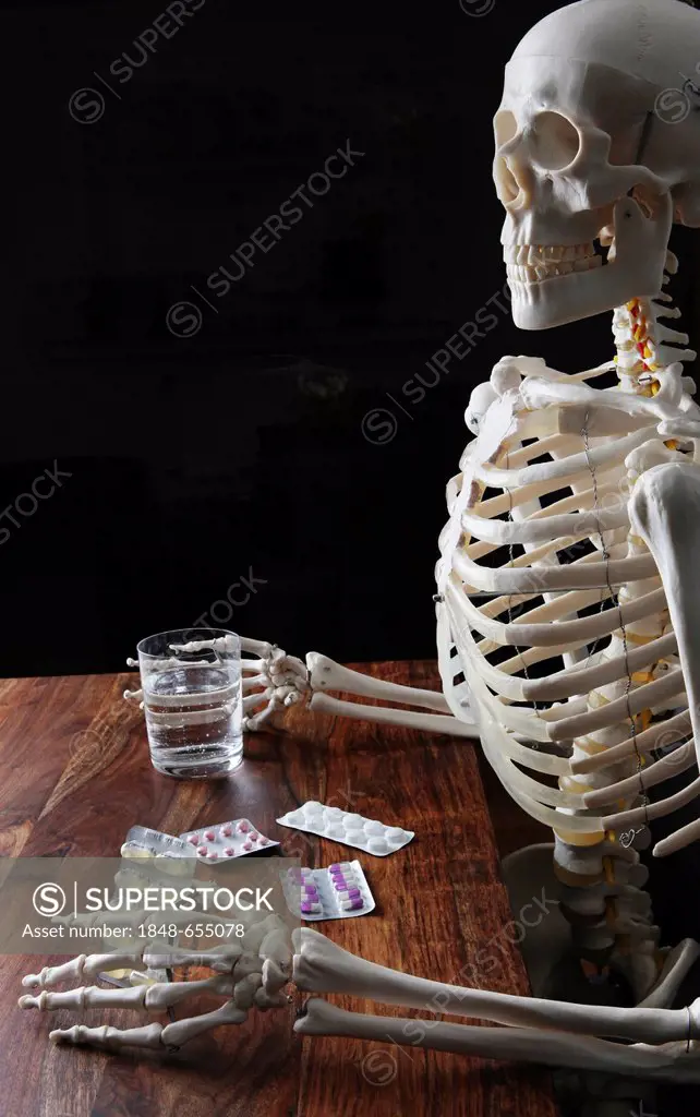 Skeleton holding tablets and a glass of water
