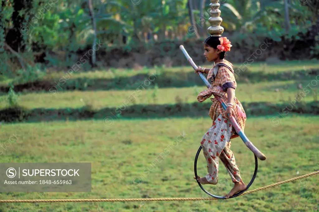 Girl balancing on a high wire on a bicycle wheel, village of Dasmangalam, Pooram Festival, Kerala, India, Asia