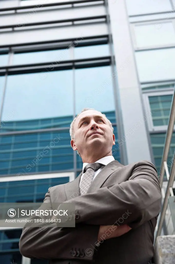 Business man with crossed arms in front of an office building