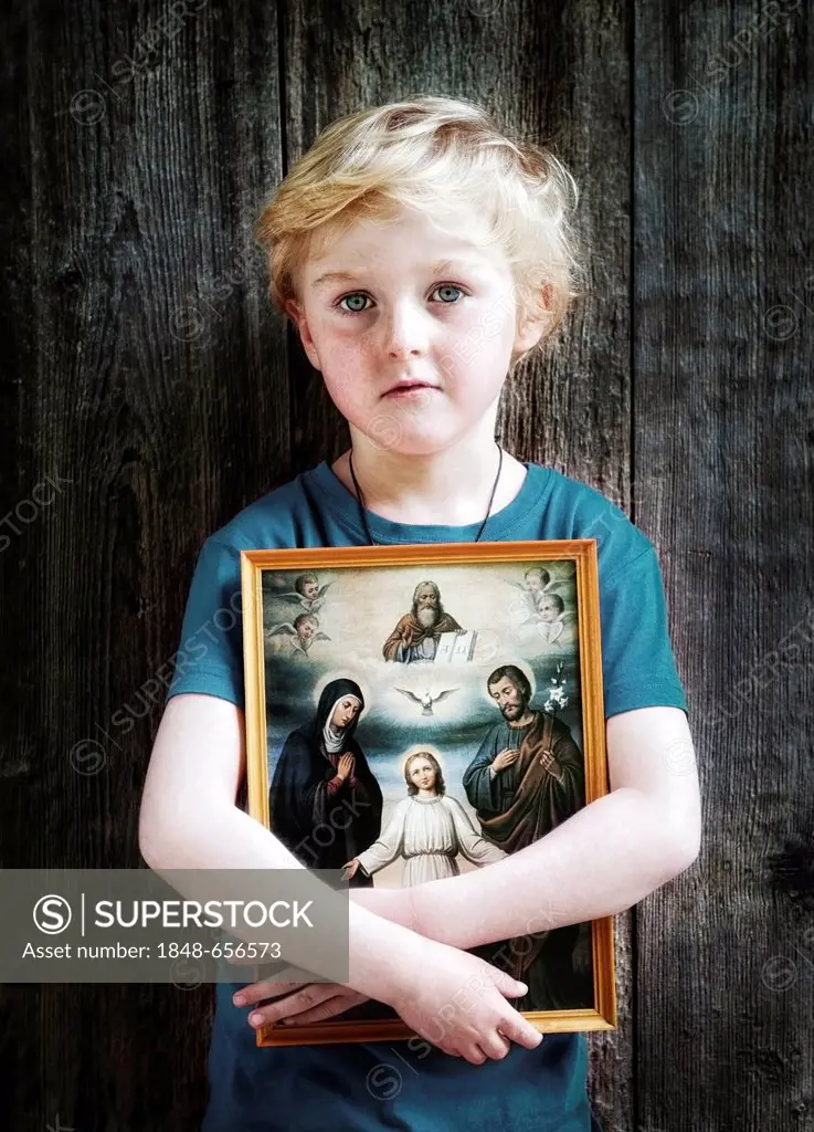 Boy holding a Christian image of saints, with Jesus, Mary and Joseph, pneuma