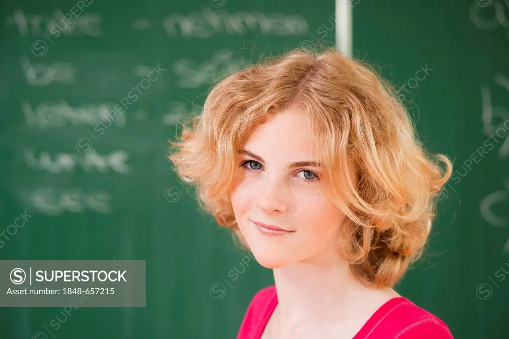 Portrait of a schoolgirl in a classroom in front of the blackboard