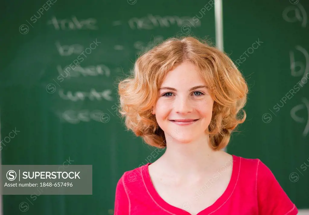 Portrait of a schoolgirl in a classroom in front of the blackboard