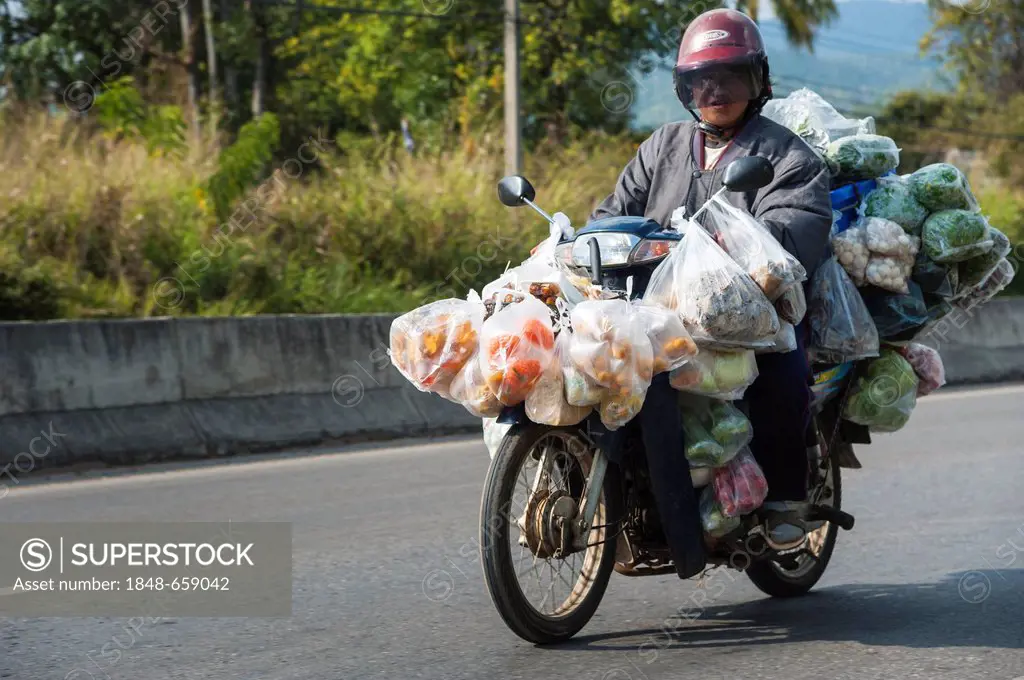 Man with many bags riding a laden motorcycle, Northern Thailand, Thailand, Asia