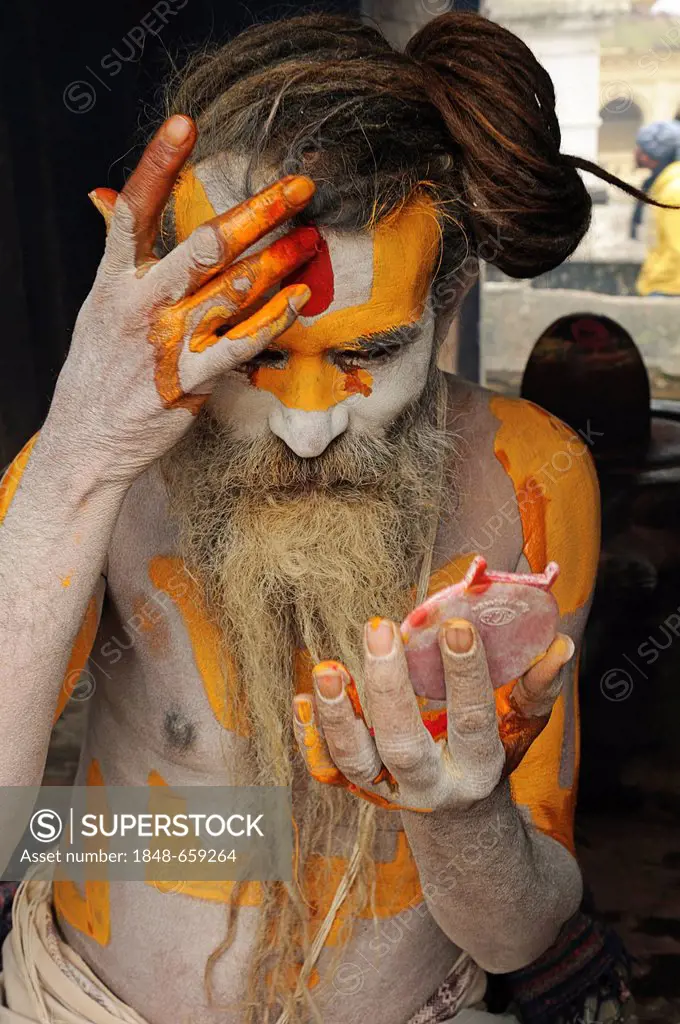 Sadhu with dreadlocks painting himself, Pashupatinath, Kathmandu Valley, Nepal