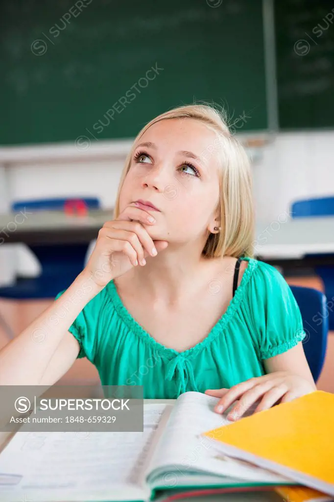 Schoolgirl sitting in a classroom and mulling over a problem