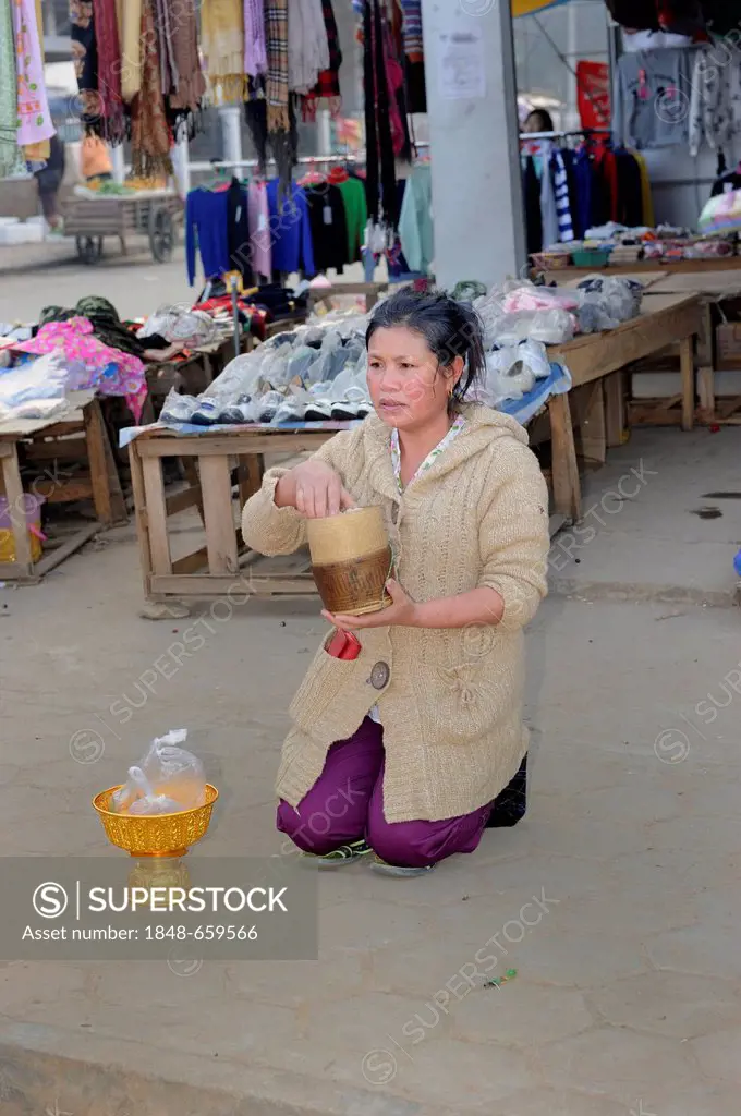 Buddhist shopkeeper waiting with offerings for the Buddhist mendicants in the early morning in the town of Phonsavan, Laos, Southeast Asia, Asia