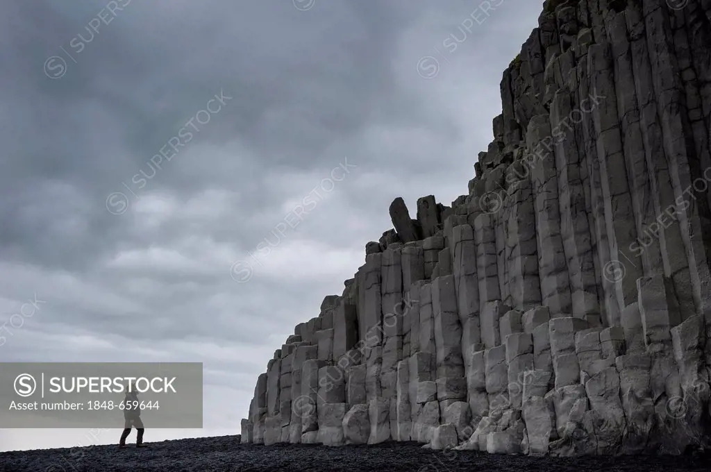 Man looking at basalt columns, Reynisfjara beach, a black beach near Vik í Mýrdal, southern coast, Iceland, Europe