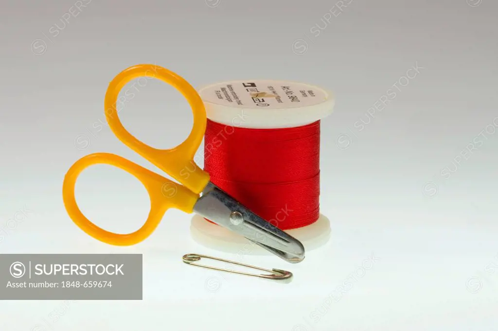 Red thread, a safety pin and a pair of scissors