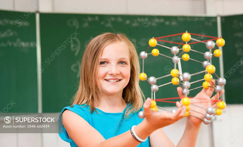 Schoolgirl in a classroom with a model of an atom