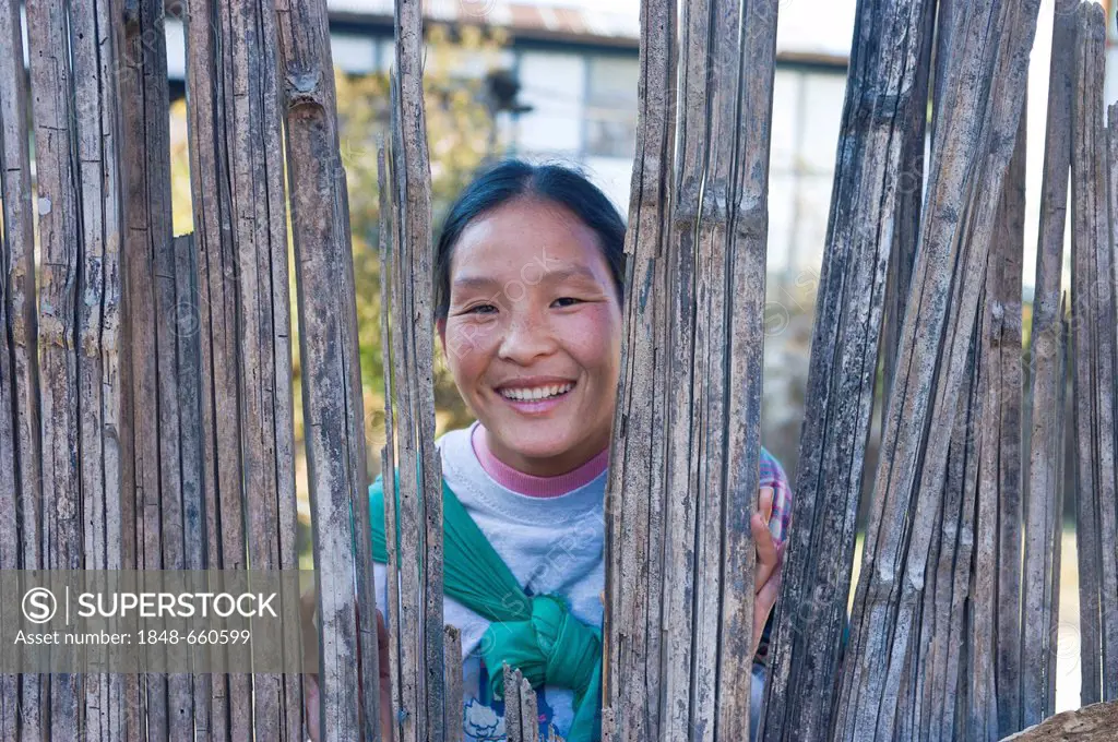 Tribal woman looks through a hole in a fence, Arunachal Pradesh, North East India, India, Asia