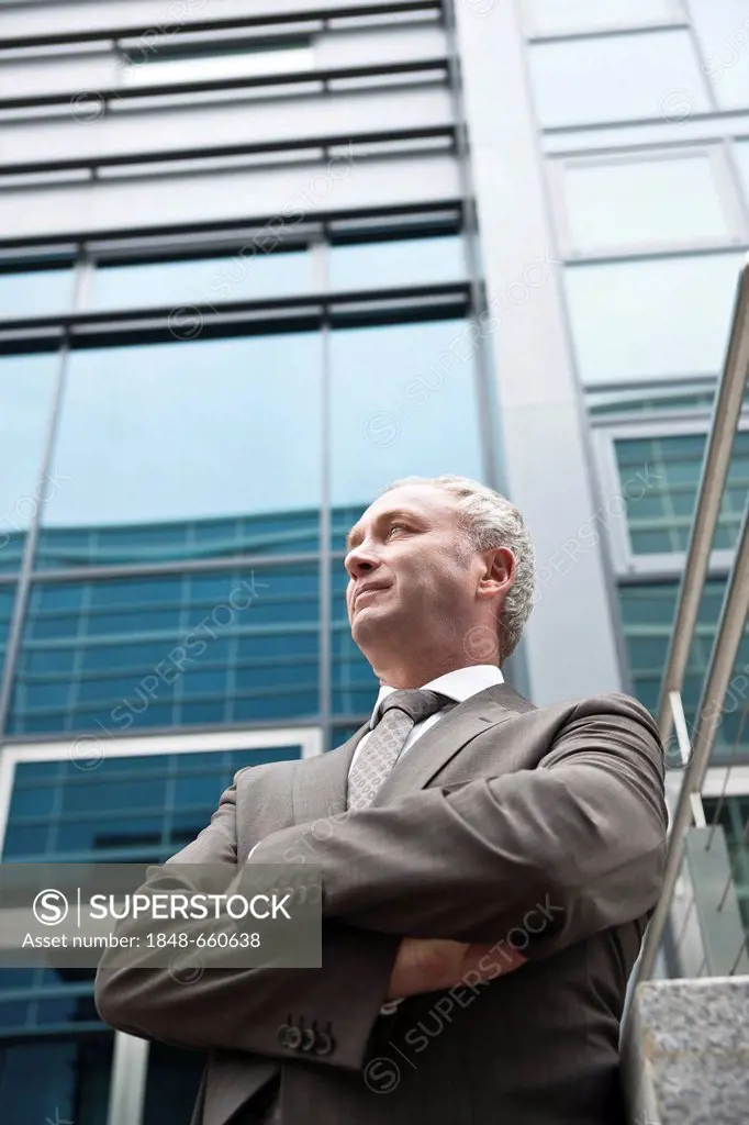 Business man with crossed arms in front of an office building