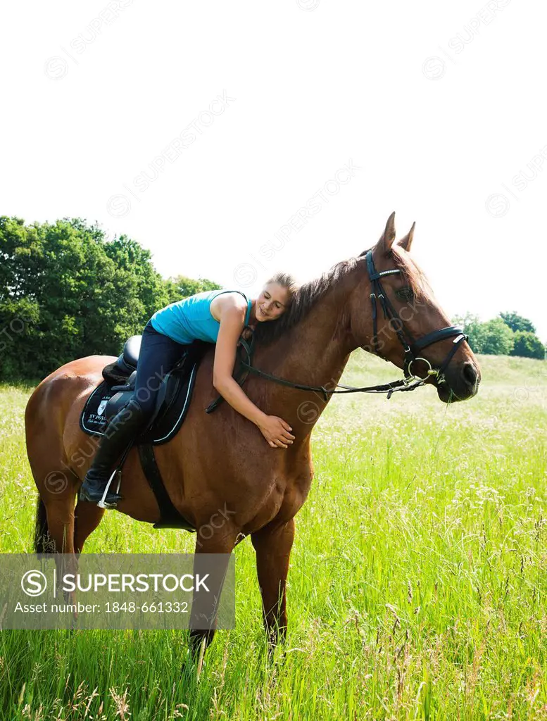 Smiling girl lying down on the neck of her horse