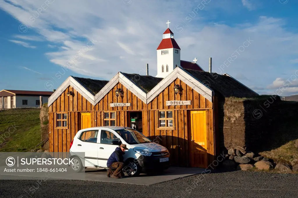 Man kneeling next to a car checking the tyre pressure, petrol station in a wooden hut, Moeðrudalur, Highlands of Iceland, Iceland, Europe