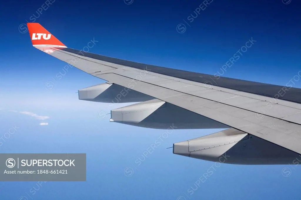 Wing of an Airbus aircraft in flight, with winglet and the logo of airline LTU, over the Atlantic Ocean