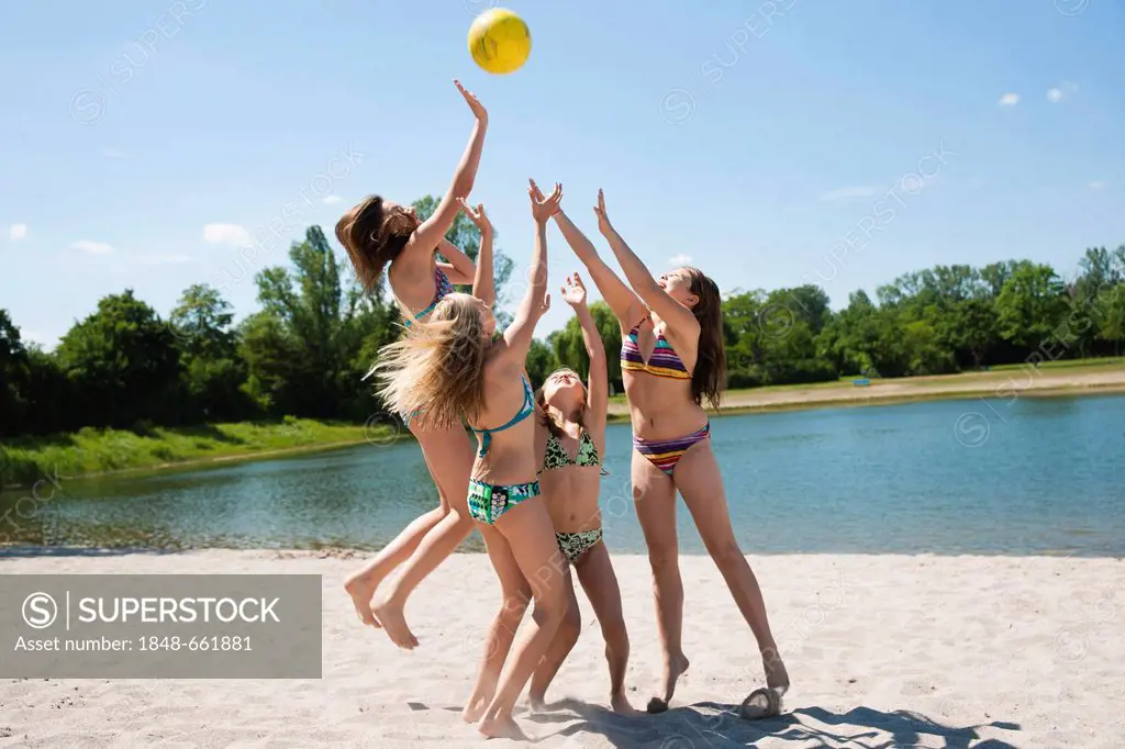 Group of girls playing with a ball on the beach of a lake