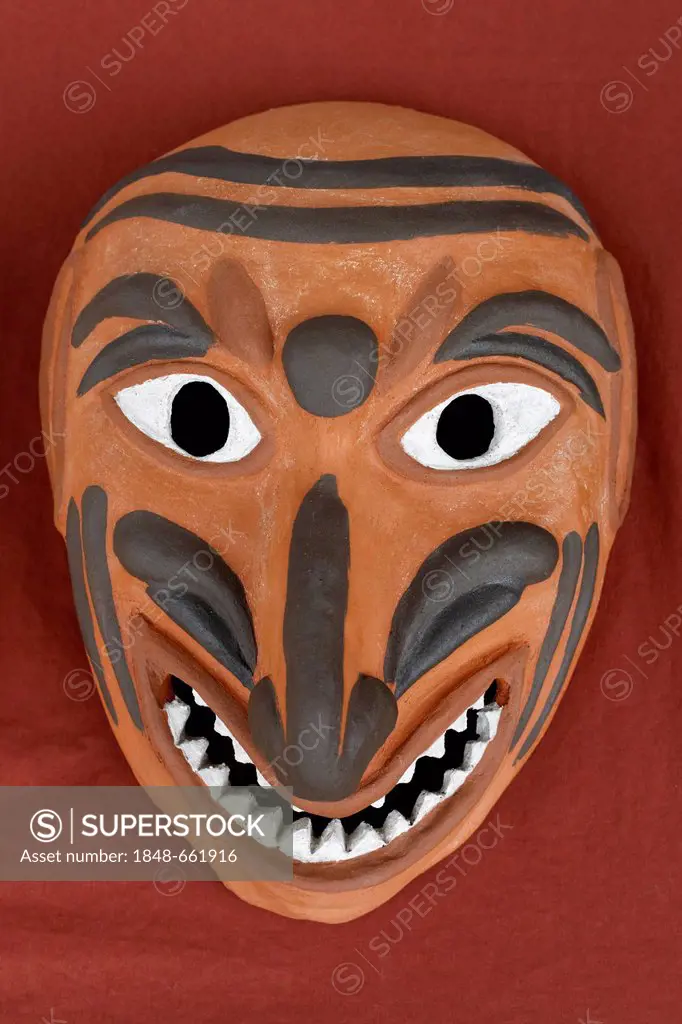 Grotesque, ugly face with pointed teeth, replica of a Roman Theatre mask made of clay, painted