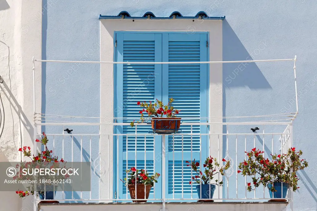 Sunny balcony, door and shutters painted in pastel blue colour, Marina di Corricella, Island of Procida, Gulf of Naples, Campania, Southern Italy, Ita...