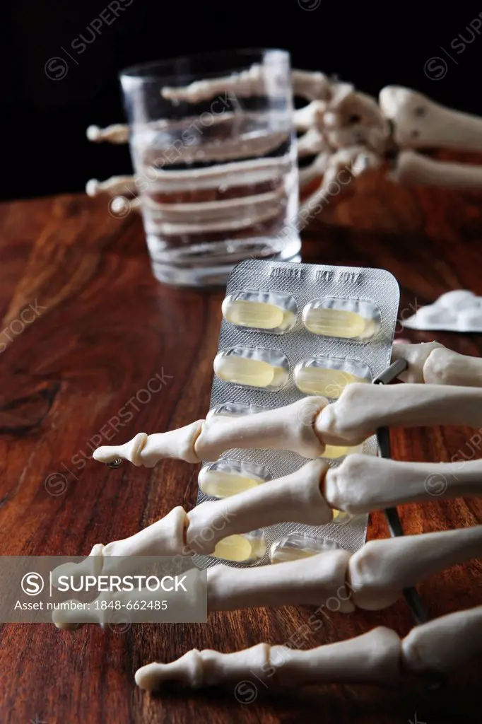 Skeleton holding tablets and a glass of water in its bony hands