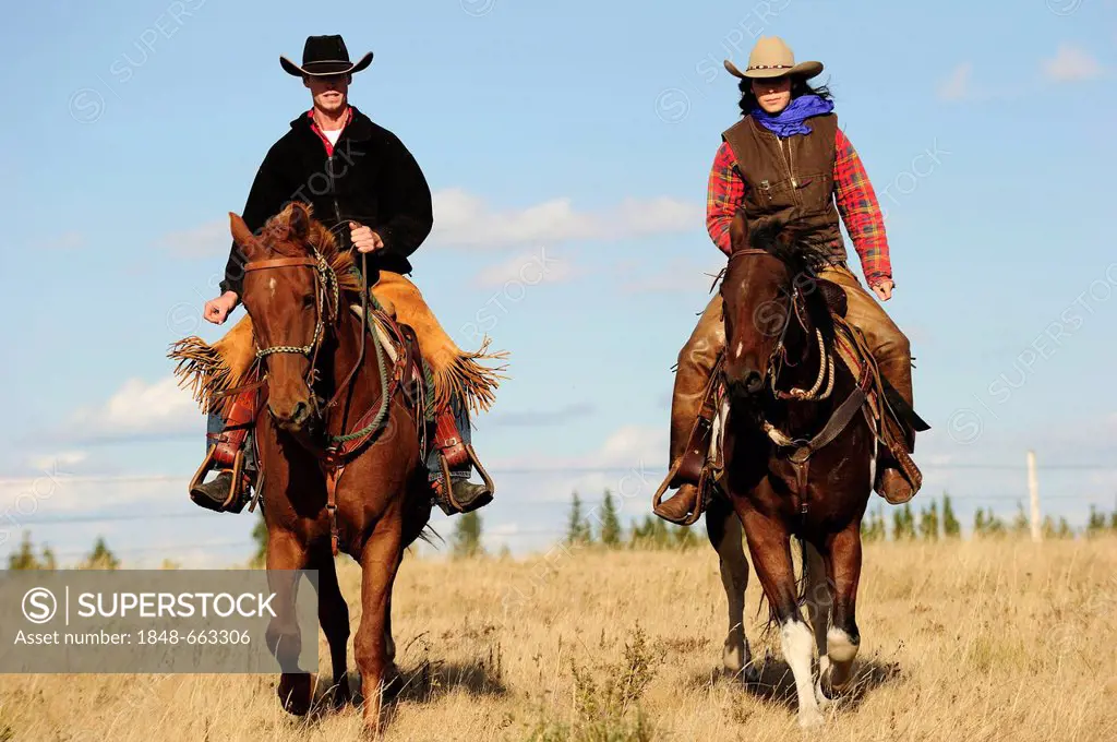 Cowboy and cowgirl riding across the prairie, Saskatchewan, Canada, North America