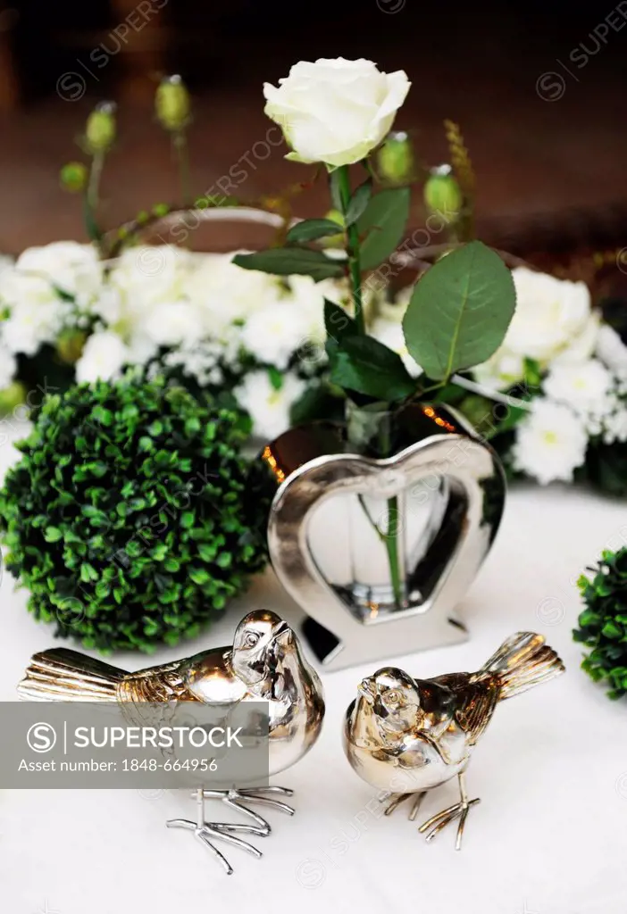 Table decoration for a wedding table, white rose in heart-shaped vase, with two birds at the front