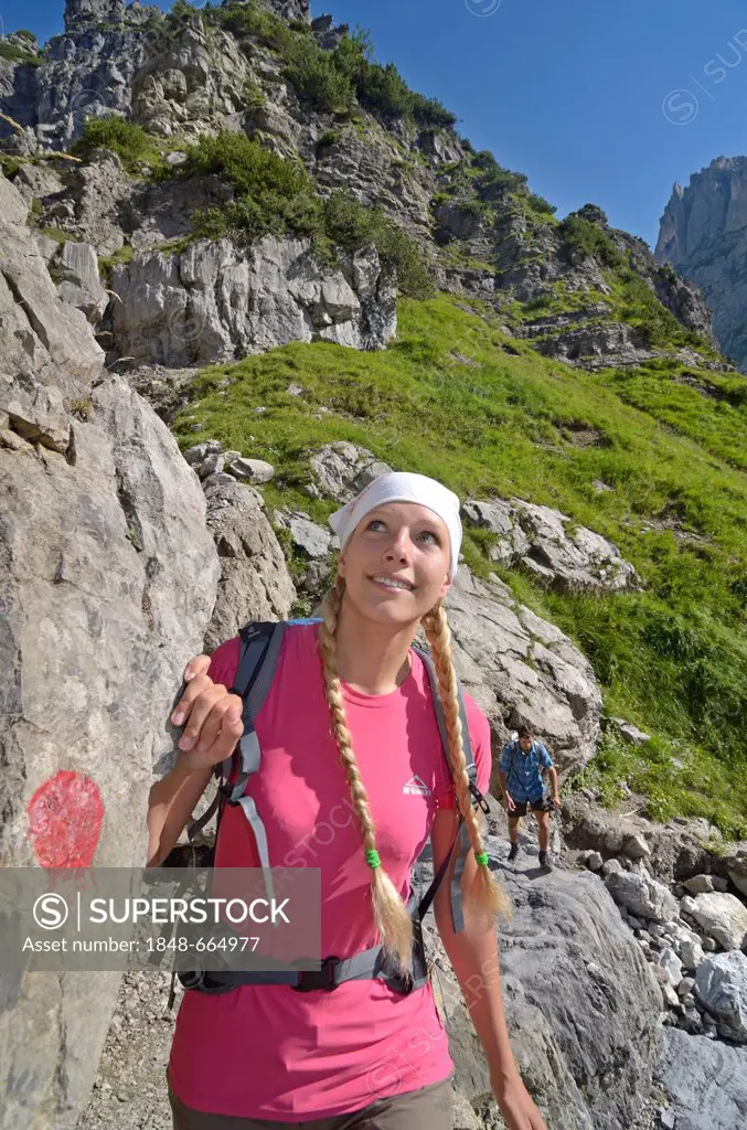 Female hiker climbing a mountain, descending past Klamml towards Gruttenhuette mountain lodge, Ellmauer Halt, Wilder Kaiser mountain, Tyrol, Austria, ...