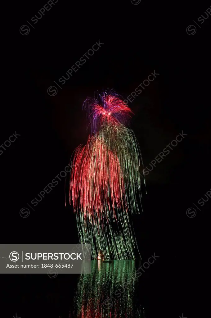 Aerial fireworks display on the lake, rockets forming waterfall, green and red light trails with reflections, Schliersee Lake, Upper Bavaria, Bavaria,...