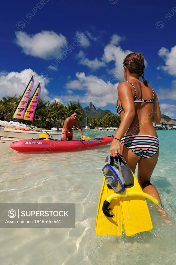 Woman taking snorkelling equipment to a kayak, St. Regis Bora Bora Resort, Bora Bora, Leeward Islands, Society Islands, French Polynesia, Pacific Ocea...