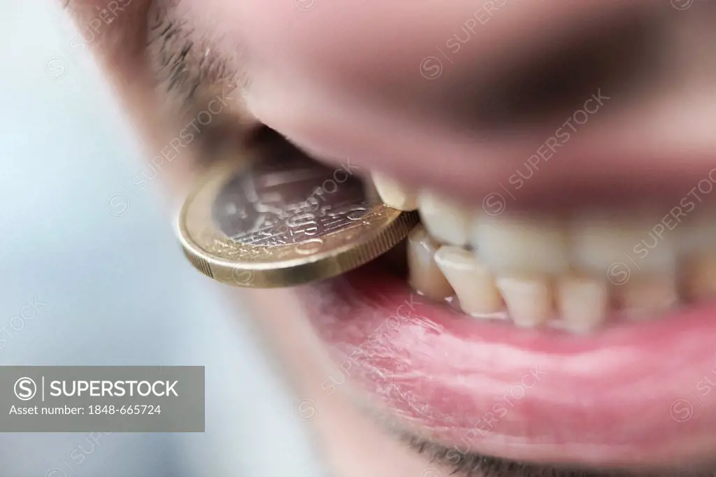 Man with an euro coin between his teeth, symbolic image for euro crisis