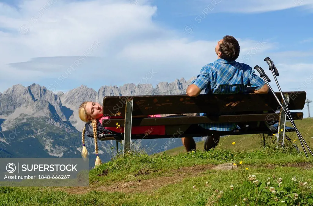 Hiker sitting on a bench on Hartkaiser mountain, Wilder Kaiser mountain at the back, Tyrol, Austria, Europe