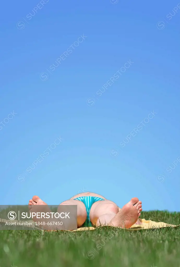 Man wearing a swimsuit lying on his back while sunbathing on a meadow