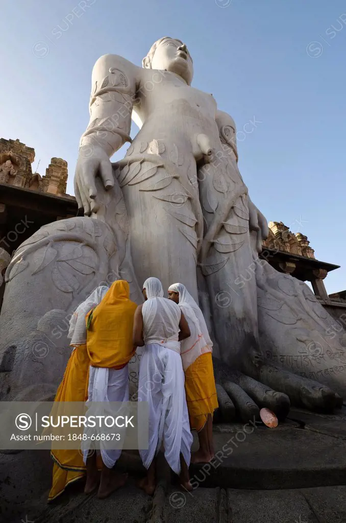 A group of Jain pilgrims doing a special pooja to receive the blessings of Bahubali by the local priests, in front of the statue of Lord Gomateshwara,...