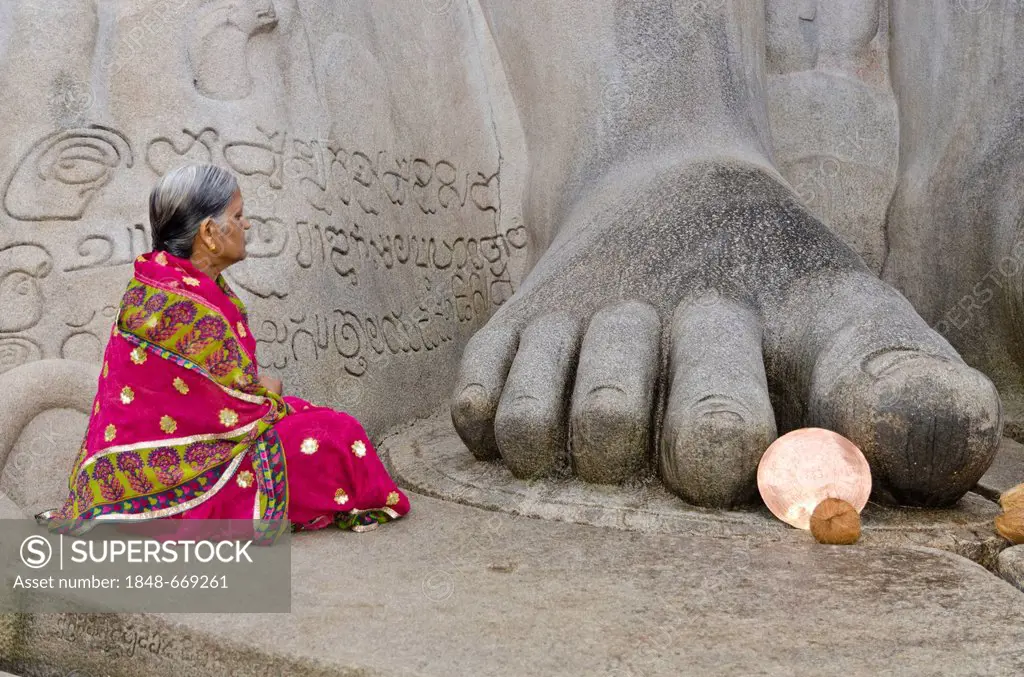 Female Jain pilgrim meditating at the feet of the statue of Lord Gomateshwara, the tallest monolithic statue in the world, dedicated to Lord Bahubali,...