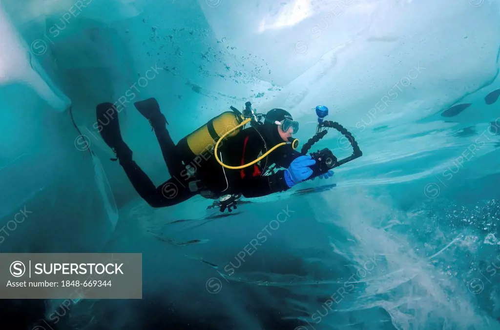 Diving photographer, ice-diving, in Lake Baikal, Olkhon island, Siberia, Russia