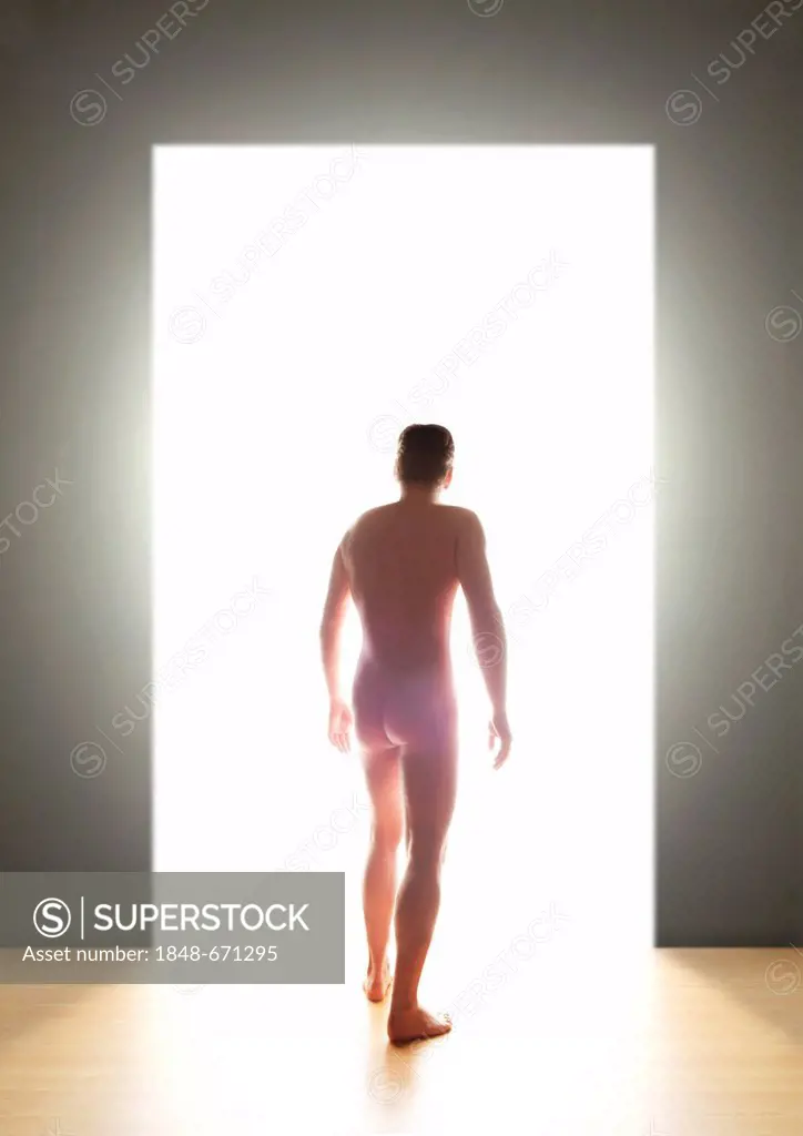 Naked young man, back view, going through a door into the light