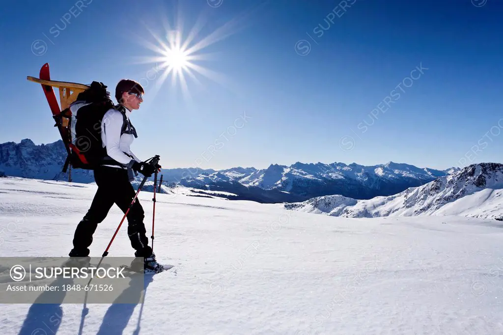 Snowshoe walker on the way from Passo Valles mountain pass to Uribrutto mountain, Dolomites, Passo Valles mountain pass at the back, province of Trent...