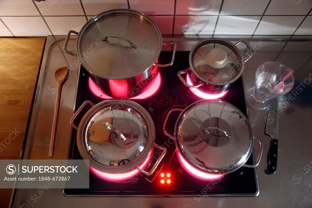 Stainless steel cooking pots on an electric stove with glass-ceramic cooktop
