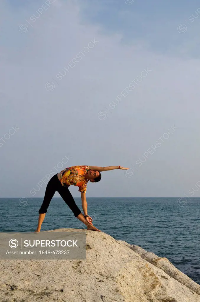 Woman in a yoga position, Trikonasana, by the sea in Kanyakumari, Tamil Nadu, India, Asia