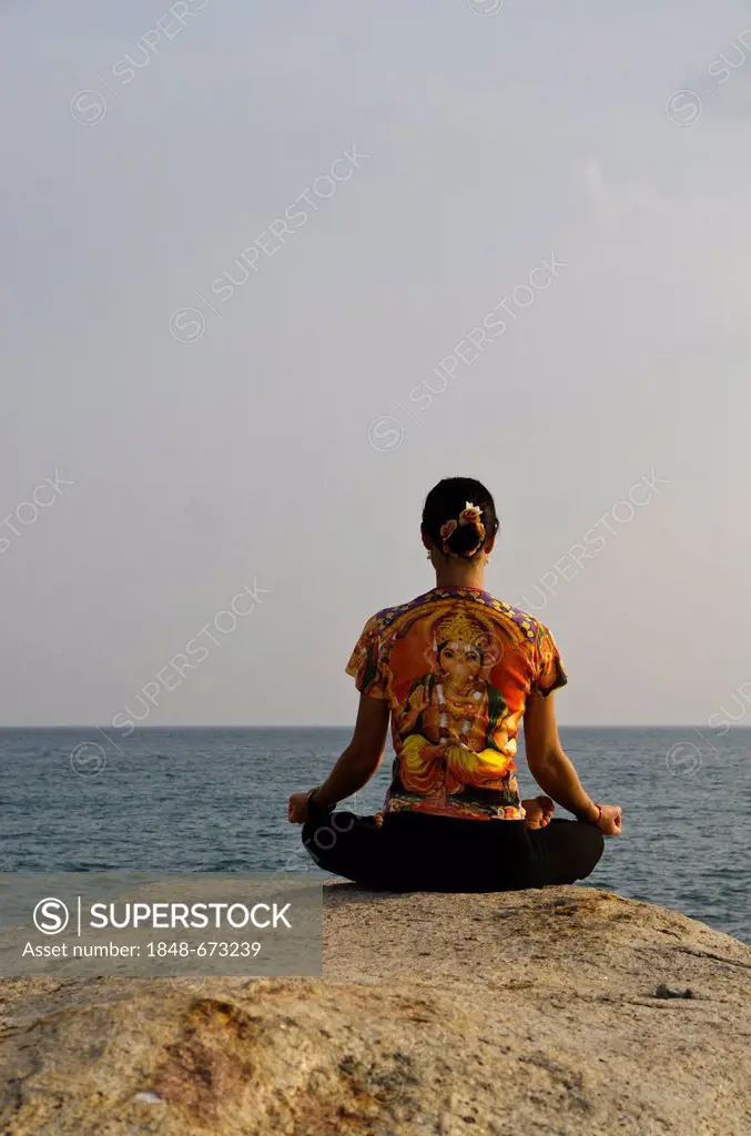 Woman in a yoga position, Padmasana, by the sea in Kanyakumari, Tamil Nadu, India, Asia