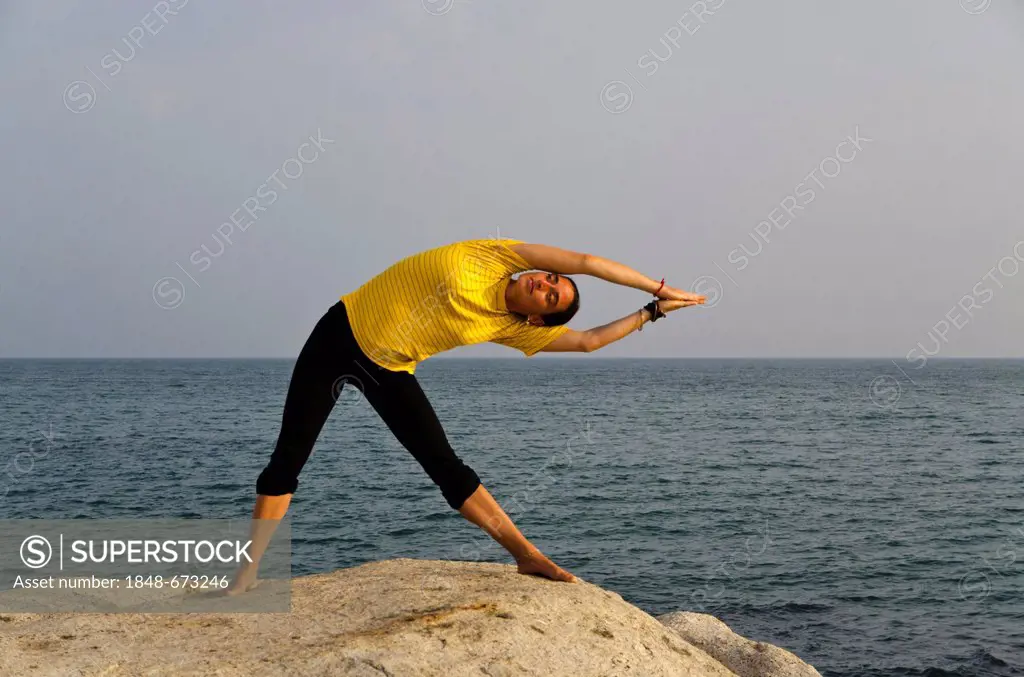 Woman in a yoga position, Trikonasana, by the sea in Kanyakumari, Tamil Nadu, India, Asia