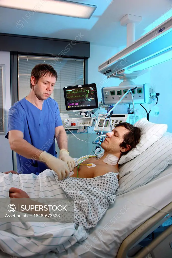 Male intensive care nurse looking after a patient lying in a special bed, medical treatment and artificial respiration of the patient, automatic monit...