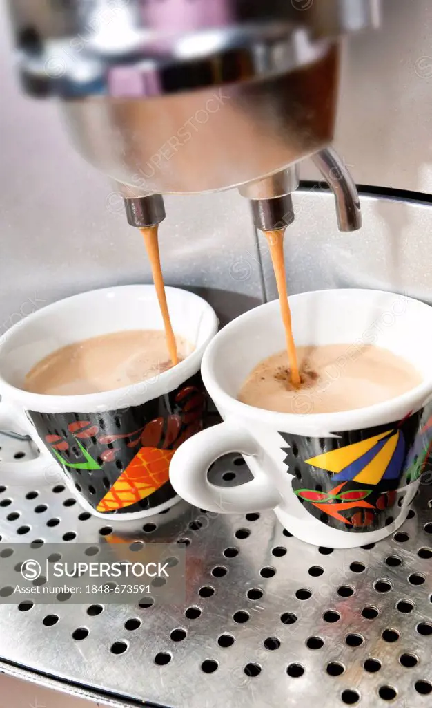 Espresso coffee machine, espresso coffee pouring from a machine into colourful espresso cups