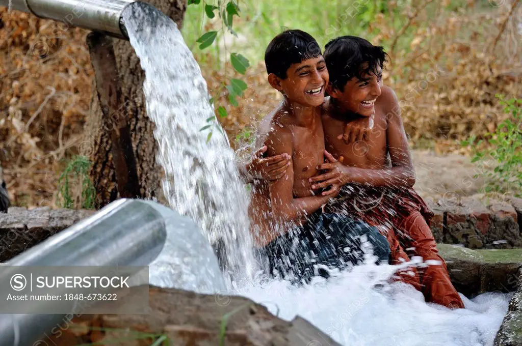 Children cooling off in the catchment of a spring fed by water pipes, Basti Lehar Walla village, Punjab, Pakistan, Asia