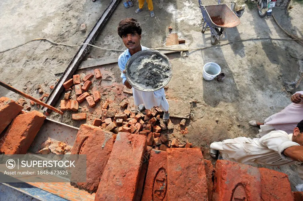 Man lifting pan with cement onto a scaffold, construction of brick houses for families whose houses were destroyed during the flood catastrophe of 201...