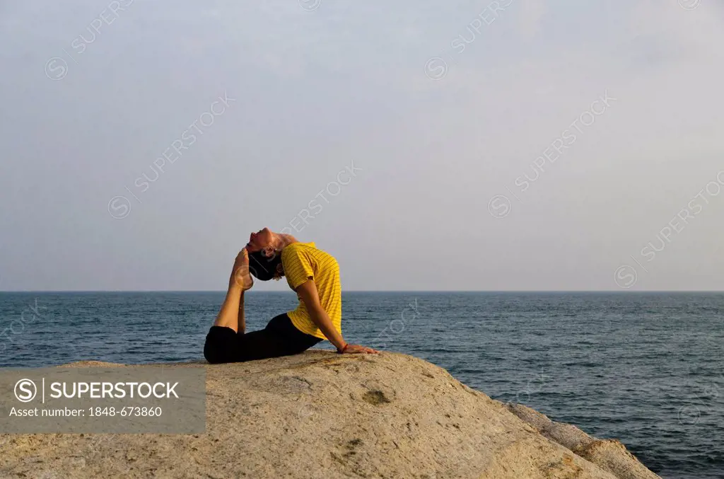 Woman in a yoga position, Bhujangasana, by the sea in Kanyakumari, Tamil Nadu, India, Asia