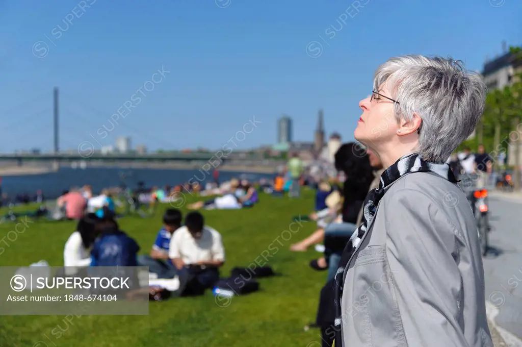 Woman enjoying the spring sunshine at the Rhine meadows, Duesseldorf, North Rhine-Westphalia, Germany, Europe