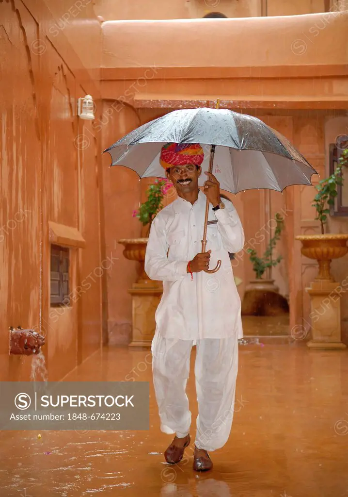 Servant with an umbrella during a monsoon rain, Khimsar Fort Heritage Hotel, Rajasthan, northern India, Asia